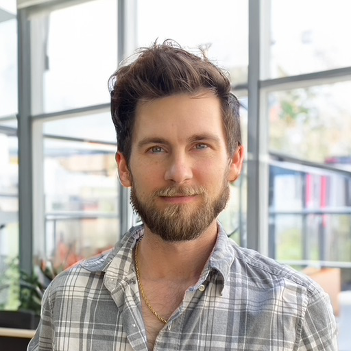 profile headshot of a handsome man stading in front of glass windows
